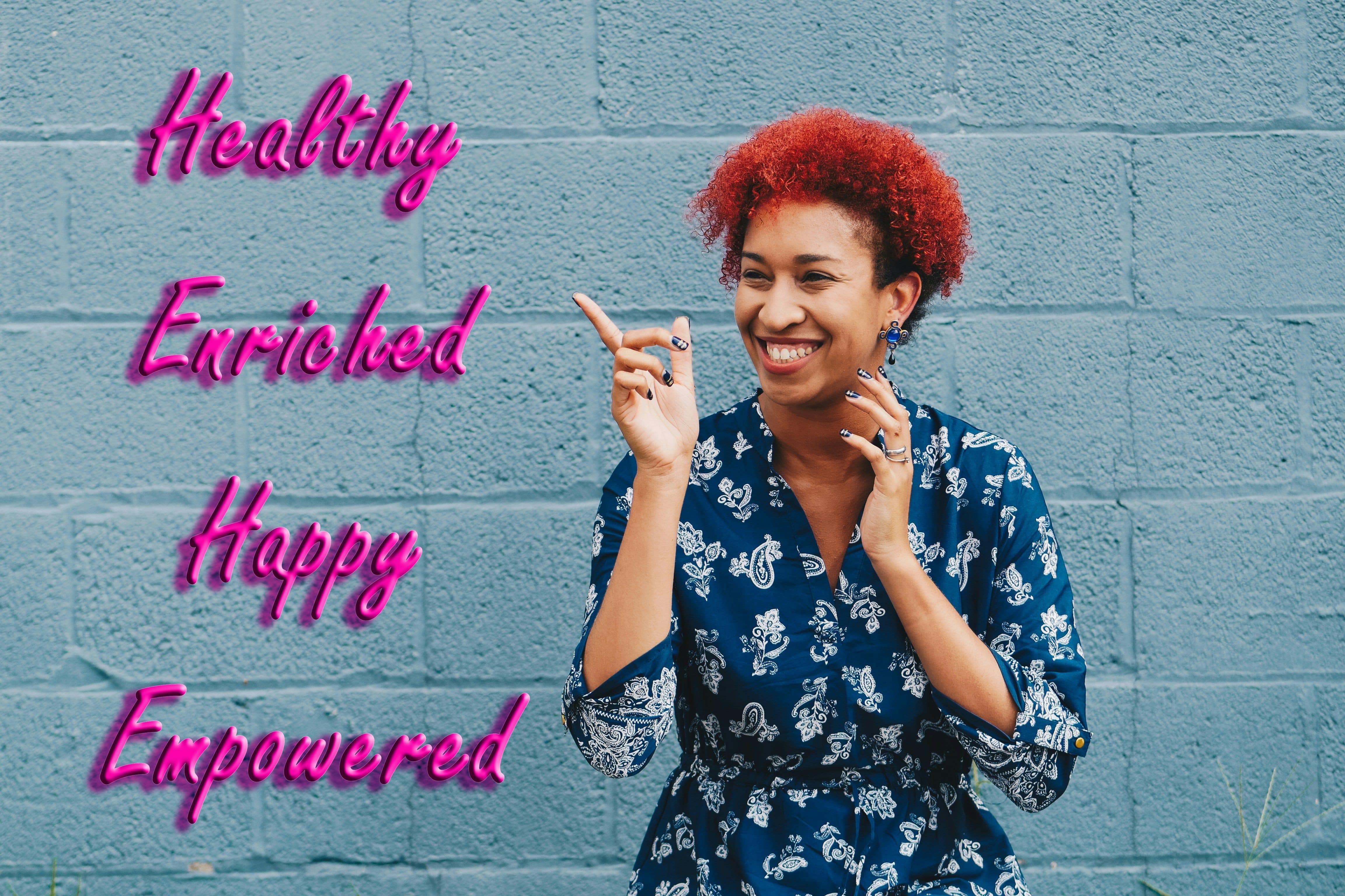 A woman is pointing the the words Healthy, Enriched, Happy, and Empowered.  Representing potential outcomes from working with Buelow Wellness.