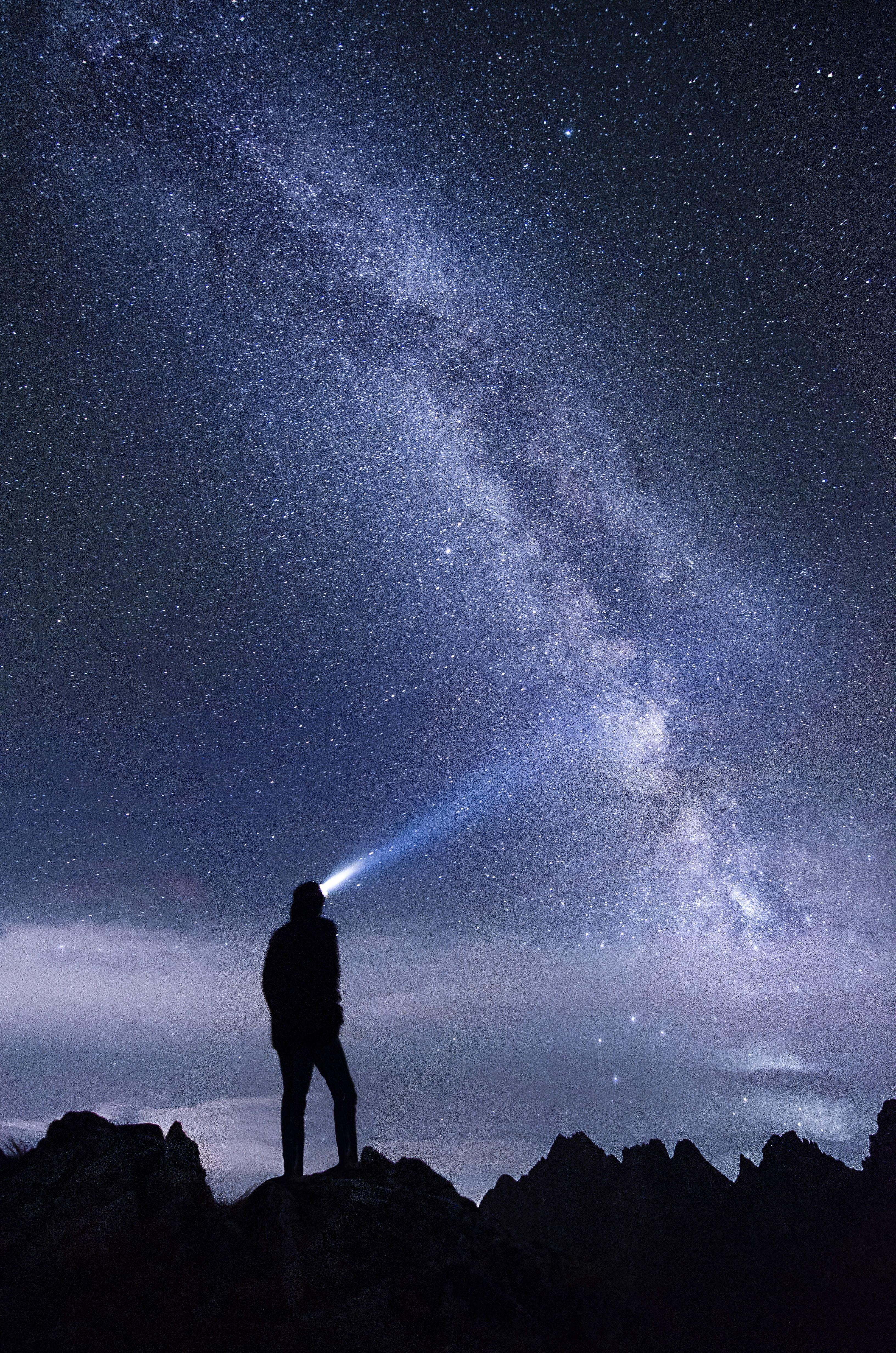 A person with a headlamp looks off into the starry night sky.  Reiki isn't hindered by time or space and can be sent to any place or time that it is intended.