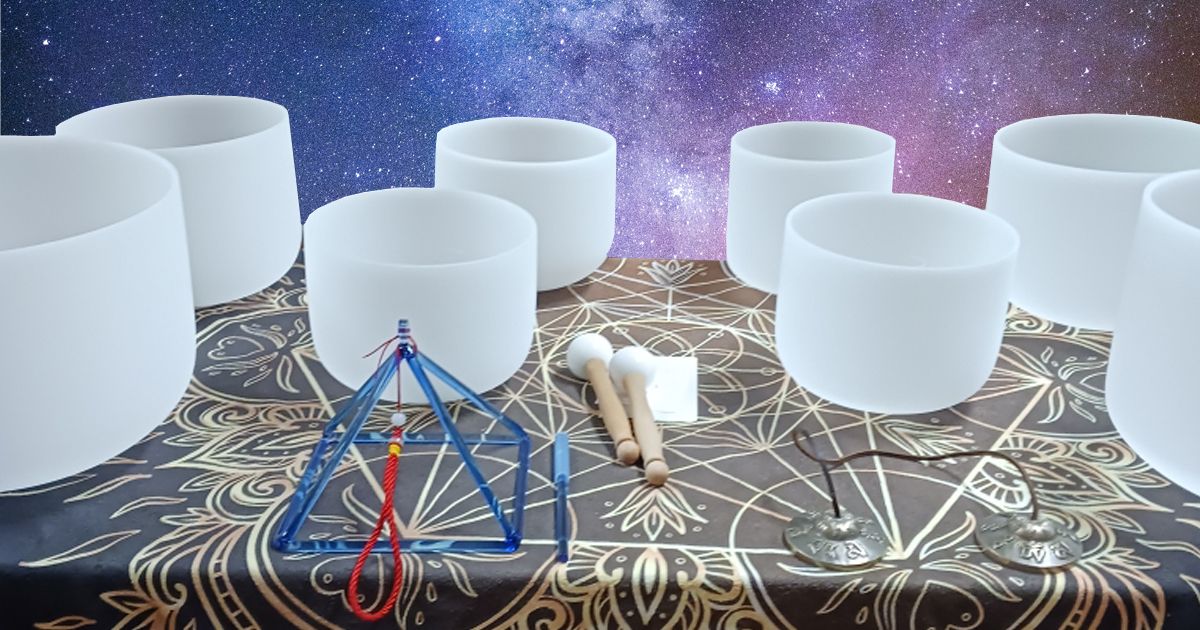 A table arranged with crystal sound bowls and a crystal pyramid to play for a sound bath of healing frequencies.